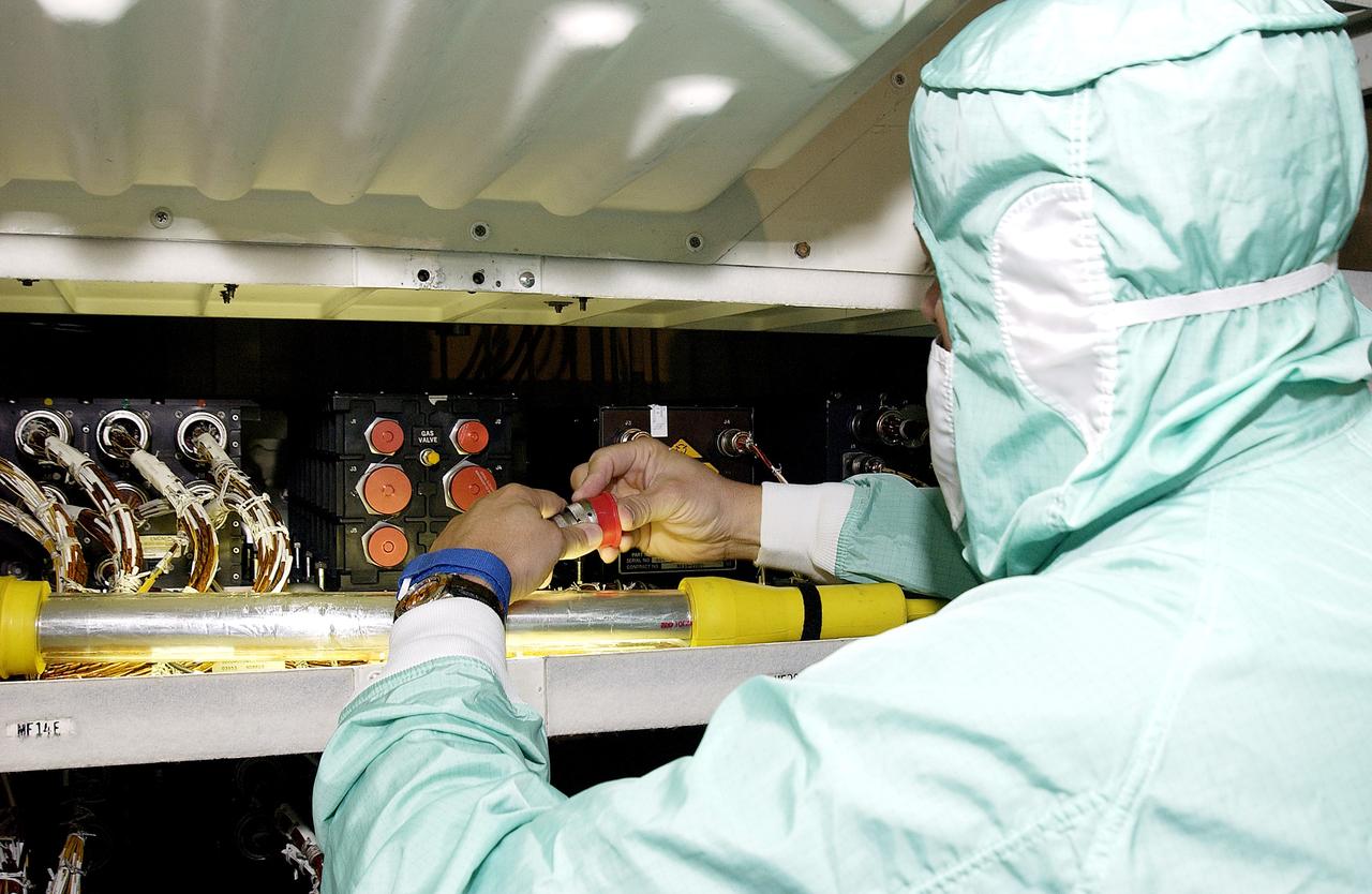 KENNEDY SPACE CENTER, FLA.  -   A technician with United Space Alliance checks wiring in the mid-body and flight deck of  orbiter Atlantis as part of routine maintenance.