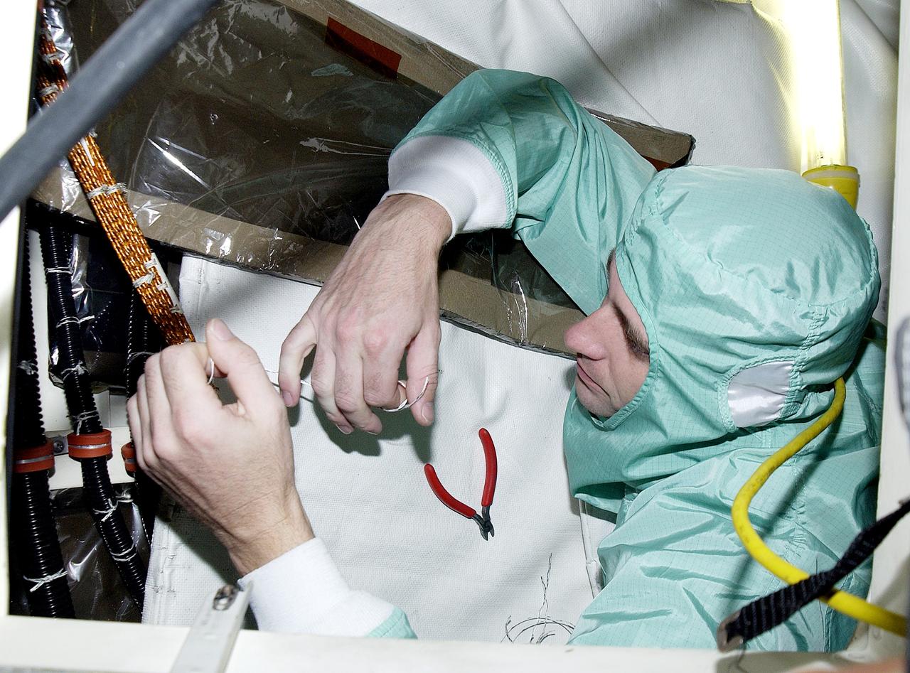 KENNEDY SPACE CENTER, FLA.  -   A technician with United Space Alliance checks wiring in the mid-body and flight deck of  orbiter Atlantis as part of routine maintenance.