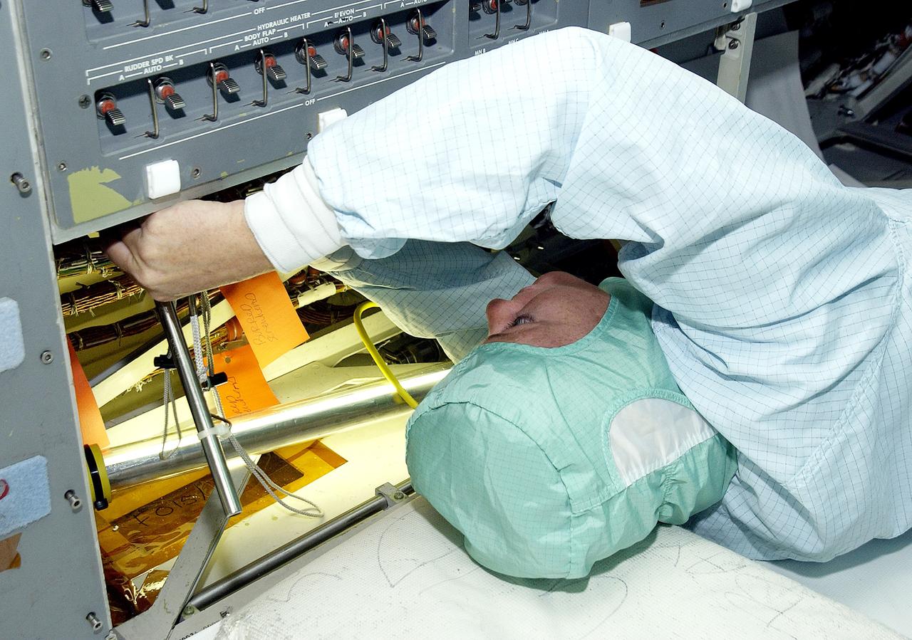 KENNEDY SPACE CENTER, FLA.  -     A technician with United Space Alliance checks wiring in the mid-body and flight deck of  orbiter Atlantis as part of routine maintenance.