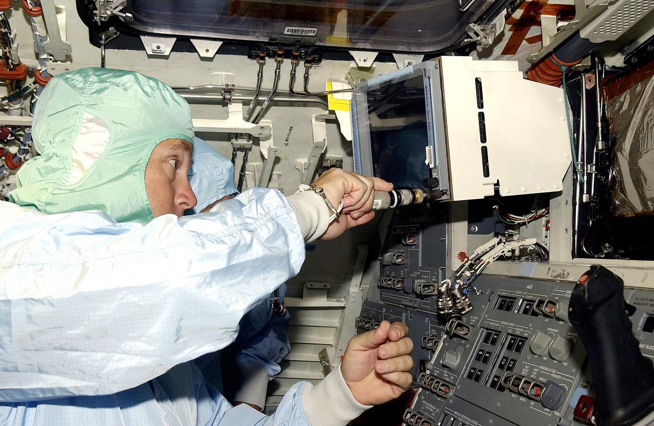 KENNEDY SPACE CENTER, FLA.  -   A technician with United Space Alliance works inside orbiter Discovery before power-up of the vehicle in the Orbiter Processing Facility .  Discovery has been undergoing Orbiter Major Modifications in the past year, ranging from wiring, control panels and black boxes to gaseous and fluid systems tubing and components.  These systems were deserviced, disassembled, inspected, modified, reassembled, checked out and reserviced, as were most other systems onboard.  The work includes the installation of the Multifunction Electronic Display Subsystem (MEDS) - a state-of-the-art “glass cockpit.”
