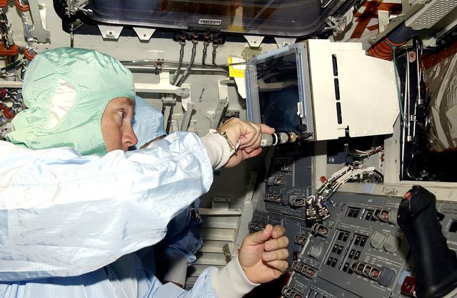 NASA image: KENNEDY SPACE CENTER, FLA.  -   A technician with United Space Alliance works inside orbiter Discovery before power-up of the vehicle in the Orbiter Processing Facility .  Discovery has been undergoing Orbiter Major Modifications in the past year, ranging from wiring, control panels and black boxes to gaseous and fluid systems tubing and components.  These systems were deserviced, disassembled, inspected, modified, reassembled, checked out and reserviced, as were most other systems onboard.  The work includes the installation of the Multifunction Electronic Display Subsystem (MEDS) - a state-of-the-art “glass cockpit.”