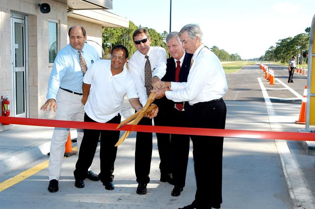 NASA image: KENNEDY SPACE CENTER, FLA.  -  Key officials are poised to cut the ribbon officially dedicating the new Security gates on Kennedy Parkway (Gate 2) and NASA Parkway (Gate 3).  From left are Wally Schroeder, with Jones, Edmunds & Associates; Bobby Porter, with Oneida Construction; Daniel Tweed, NASA project manager; Jim Kennedy, Center director; and William Sample, SGS deputy program manager.  The new gates were activated Aug. 1, allowing the general public to have access to the new Space Commerce Way, which will provide access to the Research Park and KSC Visitor Complex, and providing an alternate route for the general public between Titusville and Merritt Island that is accessible 24 hours a day.  The gates are staffed 24 hours daily.
