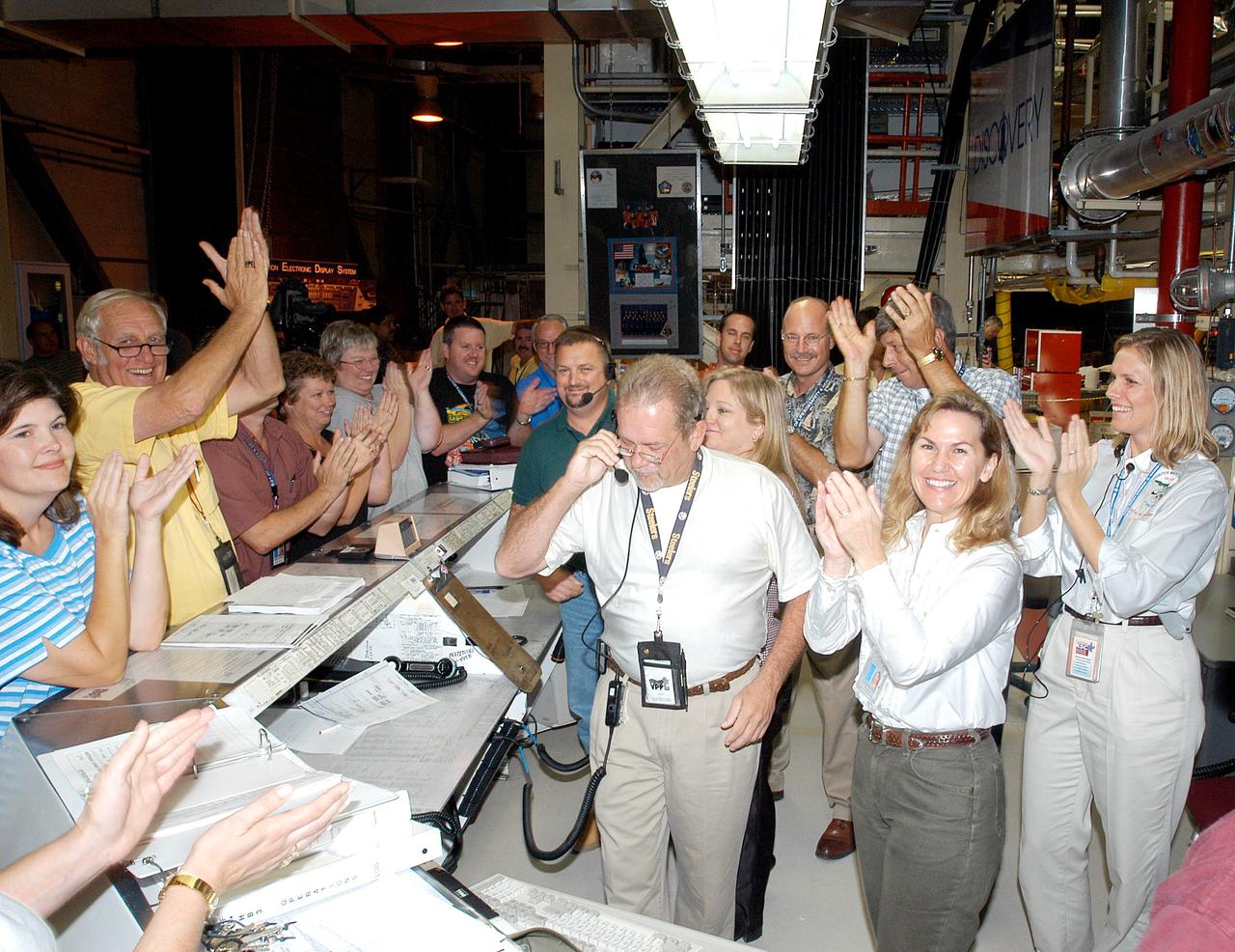 KENNEDY SPACE CENTER, FLA.  -   In the Orbiter Processing Facility, the processing team applaud the successful power-up of the orbiter Discovery.  The vehicle has been undergoing Orbiter Major Modifications in the past year, ranging from wiring, control panels and black boxes to gaseous and fluid systems tubing and components.  These systems were deserviced, disassembled, inspected, modified, reassembled, checked out and reserviced, as were most other systems onboard.  The work includes the installation of the Multifunction Electronic Display Subsystem (MEDS) - a state-of-the-art “glass cockpit.”