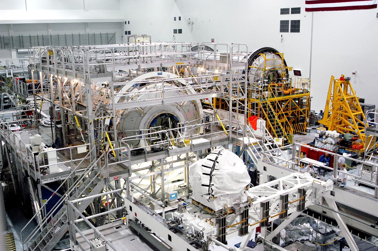 KENNEDY SPACE CENTER, FLA. - In the Space Station Processing Facility, the U.S. Node 2 (center) and the Japanese Experiment Module (JEM), background right, await a Multi-Element Integrated Test (MEIT). Node 2 attaches to the end of the U.S. Lab on the International Space Station and provides attach locations for the Japanese laboratory, European laboratory, the Centrifuge Accommodation Module and, eventually, Multipurpose Logistics Modules. It will provide the primary docking location for the Shuttle when a pressurized mating adapter is attached to Node 2.  Installation of the module will complete the U.S. Core of the ISS.  The National Space Development Agency of Japan (NASDA) developed their laboratory at the Tsukuba Space Center near Tokyo. It is the first element, named "Kibo" (Hope), to be delivered to KSC. The JEM is Japan's primary contribution to the Station. It will enhance the unique research capabilities of the orbiting complex by providing an additional environment for astronauts to conduct science experiments.