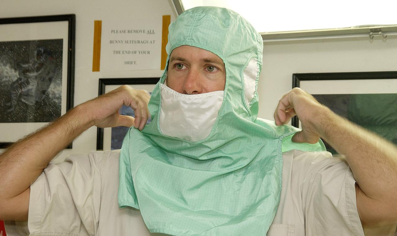 KENNEDY SPACE CENTER, FLA. - A KSC employee dons the head and face cover of a "bunny suit," part of standard clean room apparel, before entering a clean room.  This apparel is designed to cover the hair, clothing and shoes of employees to prevent particulate matter from contaminating the space flight hardware being stored or processed in the clean room and is one aspect of KSC's Foreign Object Debris (FOD) control program, an important safety initiative.