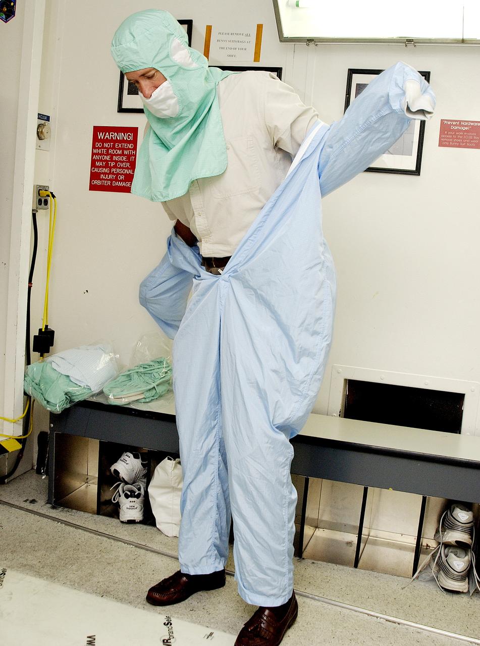 KENNEDY SPACE CENTER, FLA. -  A KSC employee dons the coverall of a "bunny suit," part of standard clean room apparel, before entering a clean room. The apparel is designed to cover the hair, clothing and shoes of employees to prevent particulate matter from contaminating the space flight hardware being stored or processed in the clean room and is one aspect of KSC's Foreign Object Debris (FOD) control program, an important safety initiative.