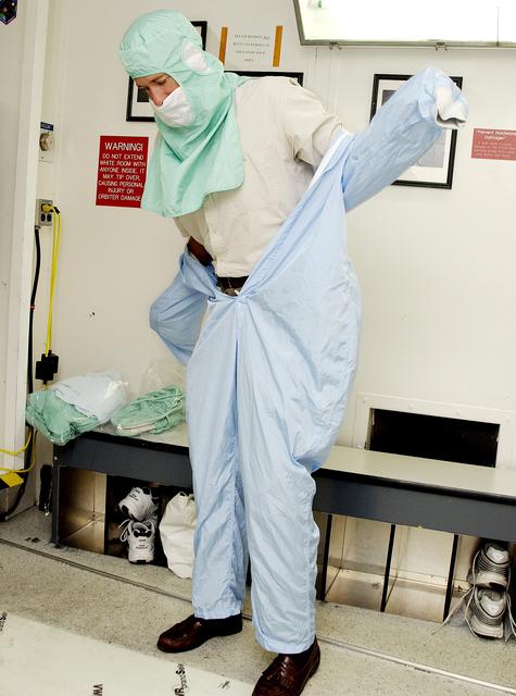 NASA image: KENNEDY SPACE CENTER, FLA. -  A KSC employee dons the coverall of a "bunny suit," part of standard clean room apparel, before entering a clean room. The apparel is designed to cover the hair, clothing and shoes of employees to prevent particulate matter from contaminating the space flight hardware being stored or processed in the clean room and is one aspect of KSC's Foreign Object Debris (FOD) control program, an important safety initiative.