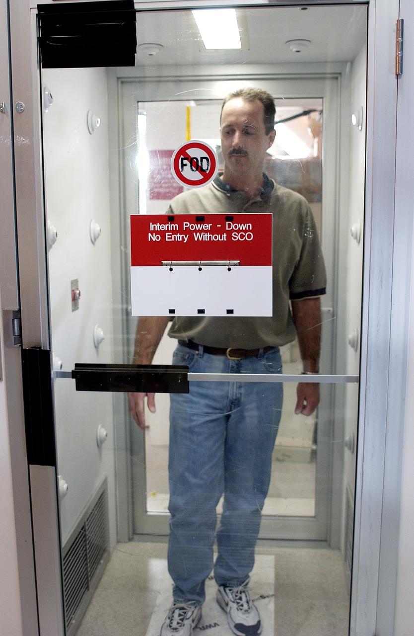 KENNEDY SPACE CENTER, FLA. -  A KSC employee uses a clean-air shower before entering a clean room.  Streams of pressurized air directed at the occupant from nozzles in the chamber's ceiling and walls are designed to dislodge particulate matter from hair, clothing and shoes.  The adhesive mat on the floor captures soil from shoe soles, as well as particles that fall on its surface.  Particulate matter has the potential to contaminate the space flight hardware being stored or processed in the clean room. The shower is part of KSC's Foreign Object Debris (FOD) control program, an important safety initiative.