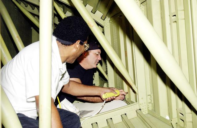 NASA image: KENNEDY SPACE CENTER, FLA. - In the Orbiter Processing Facility (OPF), United Space Alliance technicians replace the attachment points for the spars on the interior of a wing of Space Shuttle Atlantis. Reinforced Carbon Carbon (RCC) panels are mechanically attached to the wing with a series of floating joints - spars - to reduce loading on the panels caused by wing deflections. The aluminum and the metallic attachments are protected from exceeding temperature limits by internal insulation.  The next launch of Atlantis will be on mission STS-114, a utilization and logistics flight to the International Space Station.