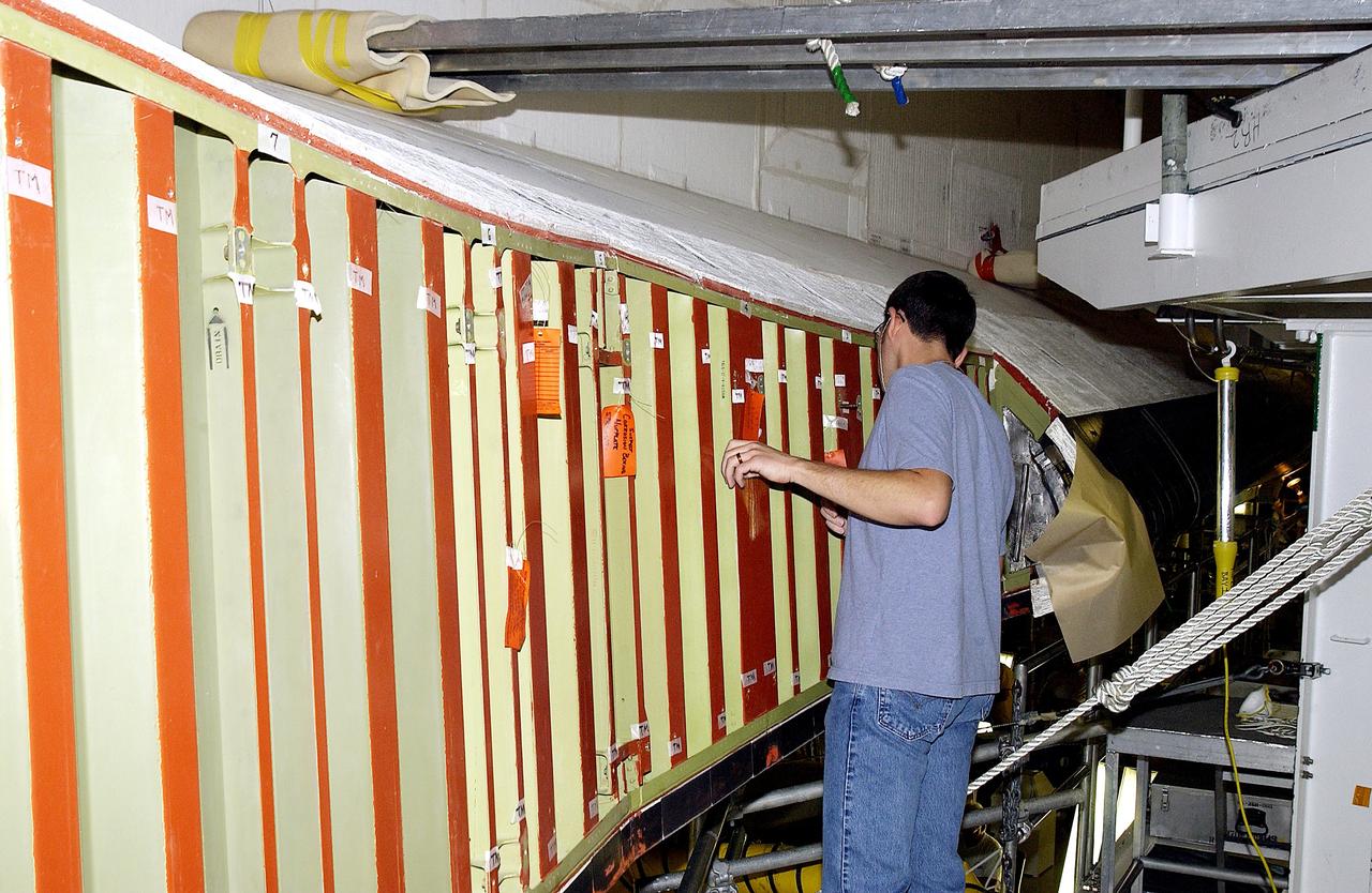 KENNEDY SPACE CENTER, FLA. - In the Orbiter Processing Facility (OPF), a United Space Alliance technician examines the attachment points for the spars on the exterior of a wing of Space Shuttle Atlantis. Reinforced Carbon Carbon (RCC) panels are mechanically attached to the wing with a series of floating joints - spars - to reduce loading on the panels caused by wing deflections. The aluminum and the metallic attachments are protected from exceeding temperature limits by internal insulation.  The next launch of Atlantis will be on mission STS-114, a utilization and logistics flight to the International Space Station.