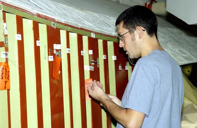 NASA image: KENNEDY SPACE CENTER, FLA. -In the Orbiter Processing Facility (OPF), a United Space Alliance technician examines the attachment points for the spars on the exterior of a wing of Space Shuttle Atlantis. Reinforced Carbon Carbon (RCC) panels are mechanically attached to the wing with a series of floating joints - spars - to reduce loading on the panels caused by wing deflections. The aluminum and the metallic attachments are protected from exceeding temperature limits by internal insulation.  The next launch of Atlantis will be on mission STS-114, a utilization and logistics flight to the International Space Station.
