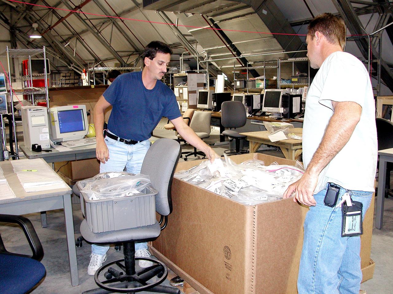KENNEDY SPACE CENTER, FLA.  -  Workers in the Columbia Debris Hangar move some of the STS-107 debris into boxes for transfer to storage in the Vehicle Assembly Building.   About 83,000 pieces were shipped to KSC during search and recovery efforts in East Texas.