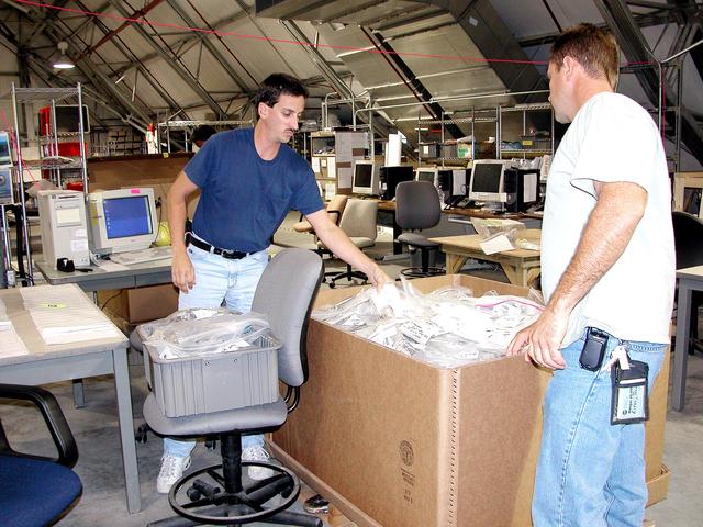 NASA image: KENNEDY SPACE CENTER, FLA.  -  Workers in the Columbia Debris Hangar move some of the STS-107 debris into boxes for transfer to storage in the Vehicle Assembly Building.   About 83,000 pieces were shipped to KSC during search and recovery efforts in East Texas.