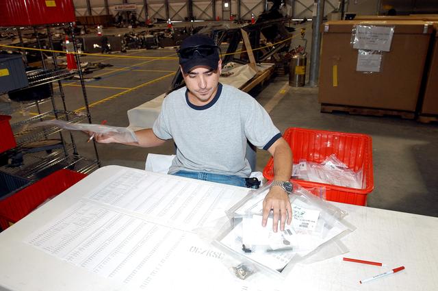 NASA image: KENNEDY SPACE CENTER, FLA.  -  A worker in the Columbia Debris Hangar sorts bagged items of Columbia debris that will be transferred to storage in the Vehicle Assembly Building.  About 83,000 pieces were shipped to KSC during search and recovery efforts in East Texas.