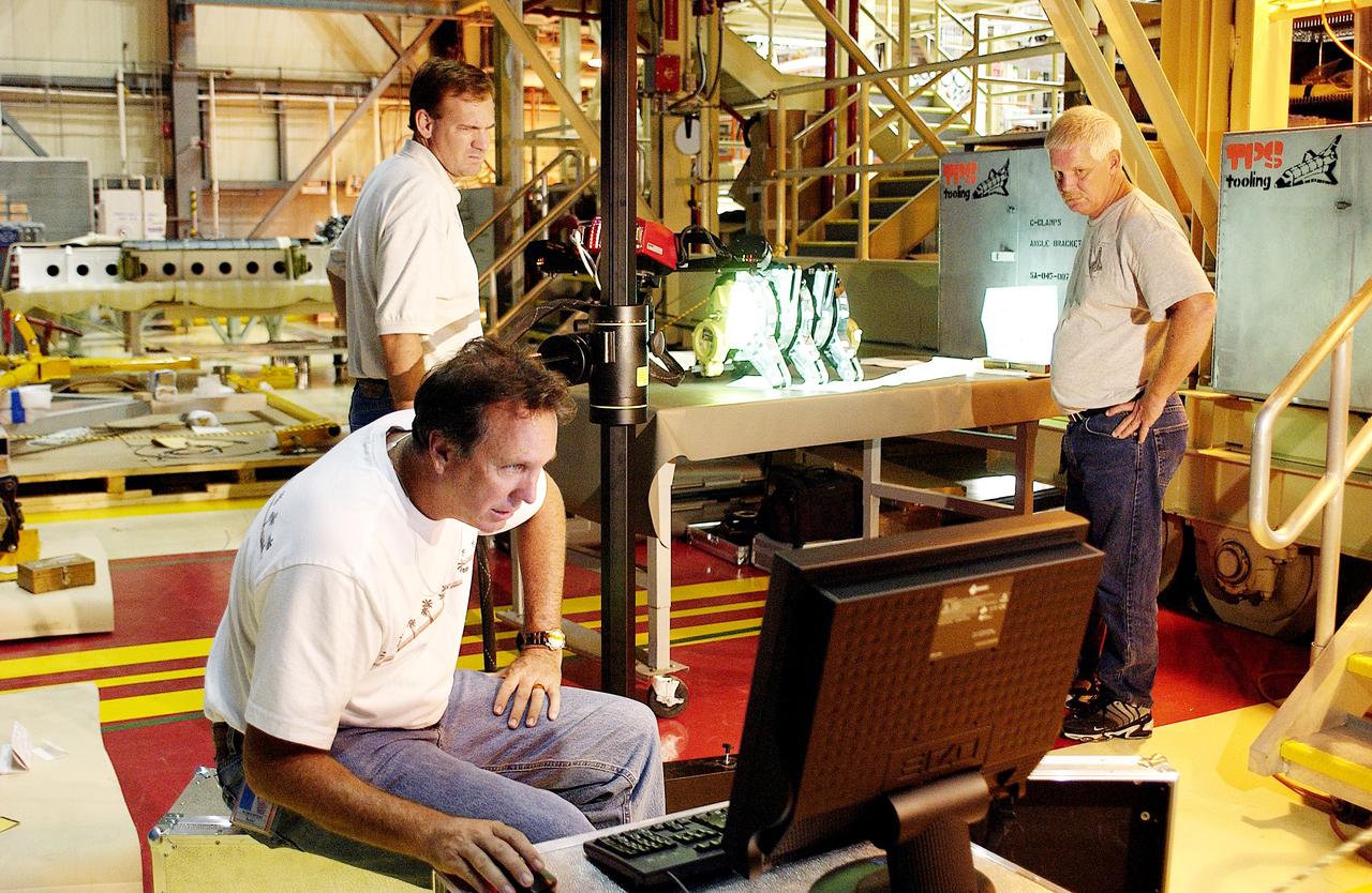 KENNEDY SPACE CENTER, FLA. -  John Macke (standing, left), with Boeing St. Louis, Alden Pitard (seated, left) and Dan Clark (right), with KSC Boeing, look at a monitor after 3D digital scanning of actuators in the Orbiter Processing Facility.  There are two actuators per engine on the Shuttle, one for pitch motion and one for yaw motion. The Space Shuttle Main Engine hydraulic servoactuators are used to gimbal the main engine.