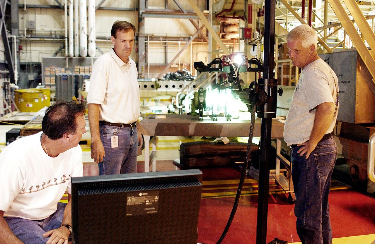 KENNEDY SPACE CENTER, FLA. -  John Macke (standing, center), with Boeing St. Louis, Alden Pitard (seated, left) and Dan Clark (right), with KSC Boeing, check results after 3D digital scanning of actuators in the Orbiter Processing Facility.  There are two actuators per engine on the Shuttle, one for pitch motion and one for yaw motion. The Space Shuttle Main Engine hydraulic servoactuators are used to gimbal the main engine.