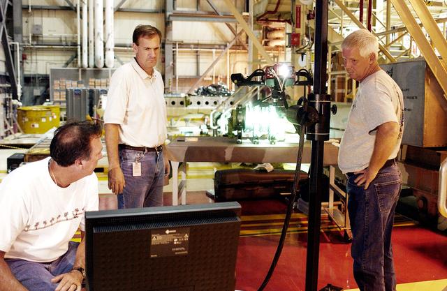 NASA image: KENNEDY SPACE CENTER, FLA. -  John Macke (standing, center), with Boeing St. Louis, Alden Pitard (seated, left) and Dan Clark (right), with KSC Boeing, check results after 3D digital scanning of actuators in the Orbiter Processing Facility.  There are two actuators per engine on the Shuttle, one for pitch motion and one for yaw motion. The Space Shuttle Main Engine hydraulic servoactuators are used to gimbal the main engine.
