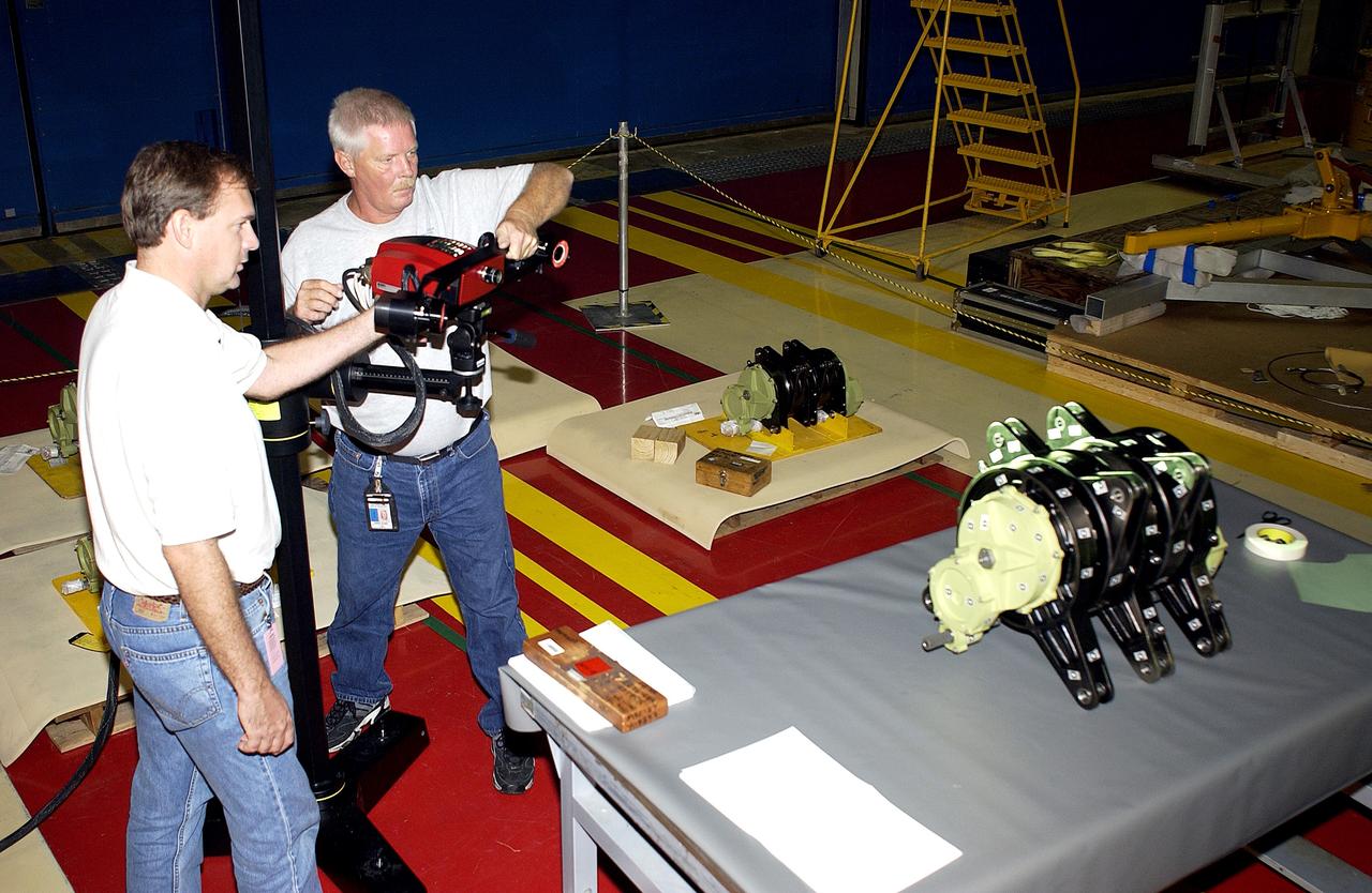 KENNEDY SPACE CENTER, FLA. -   Boeing workers get ready to perform a 3D digital scan of the actuator on the table.  At left is John Macke, from Boeing, St. Louis.   At right is Dan Clark.. There are two actuators per engine on the Shuttle, one for pitch motion and one for yaw motion. The Space Shuttle Main Engine hydraulic servoactuators are used to gimbal the main engine.