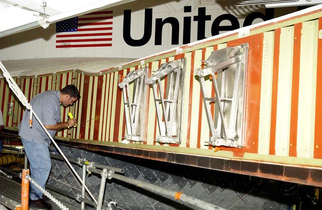 NASA image: KENNEDY SPACE CENTER, FLA. - In the Orbiter Processing Facility, John Newport, with United Space Alliance, inspects the wing of the orbiter Atlantis before installing a spar. Reinforced Carbon Carbon (RCC) panels are mechanically attached to the wing with a series of floating joints - spars - to reduce loading on the panels caused by wing deflections. The aluminum and the metallic attachments are protected from exceeding temperature limits by internal insulation.