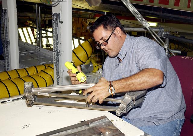 NASA image: KENNEDY SPACE CENTER, FLA. - In the Orbiter Processing Facility, John Newport, with United Space Alliance, inspects a spar to be installed on the wing of the orbiter Atlantis.  Reinforced Carbon Carbon (RCC) panels are mechanically attached to the wing with a series of floating joints - spars - to reduce loading on the panels caused by wing deflections. The aluminum and the metallic attachments are protected from exceeding temperature limits by internal insulation.