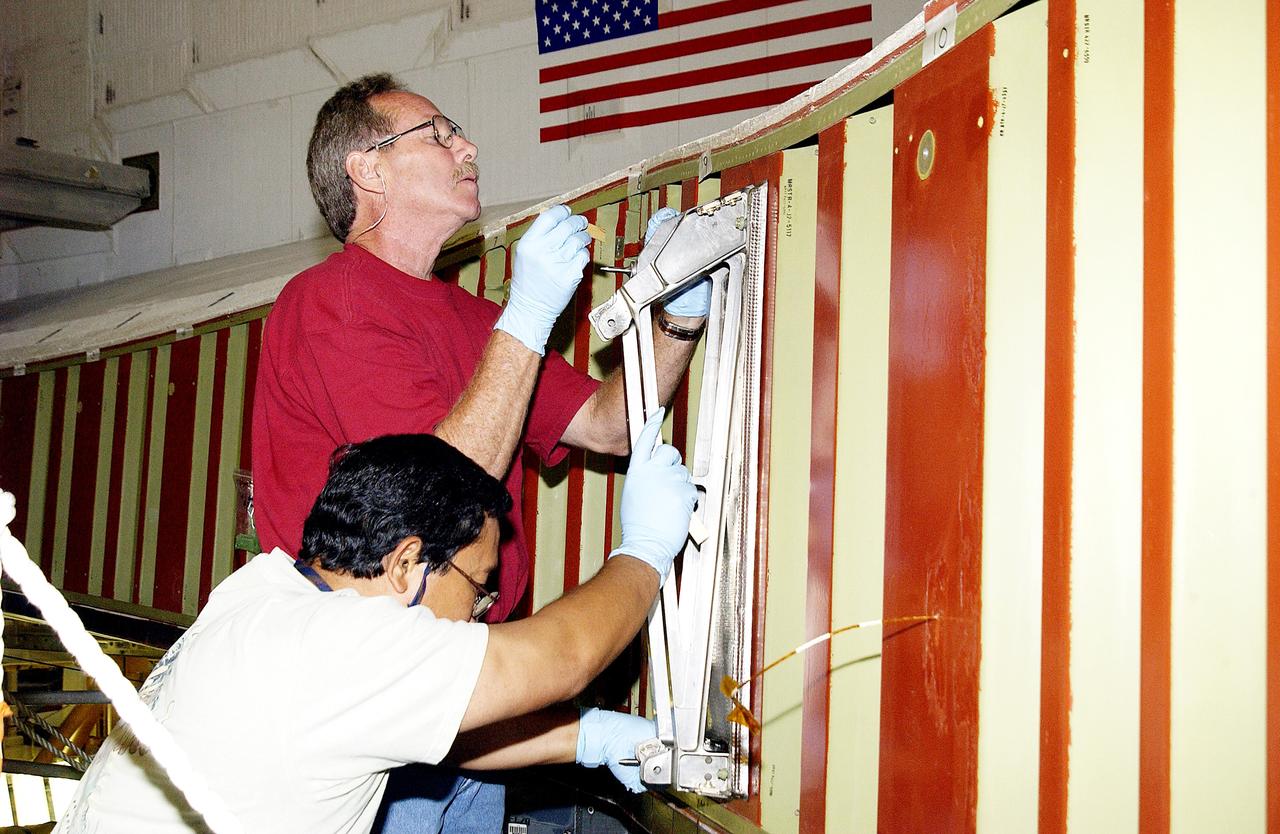 KENNEDY SPACE CENTER, FLA. - In the Orbiter Processing Facility, Mike Hyatt (above) and Saul Ngy (below), with United Space Alliance, install a spar on the wing of the orbiter Atlantis.  Reinforced Carbon Carbon (RCC) panels are mechanically attached to the wing with a series of floating joints - spars - to reduce loading on the panels caused by wing deflections. The aluminum and the metallic attachments are protected from exceeding temperature limits by internal insulation.