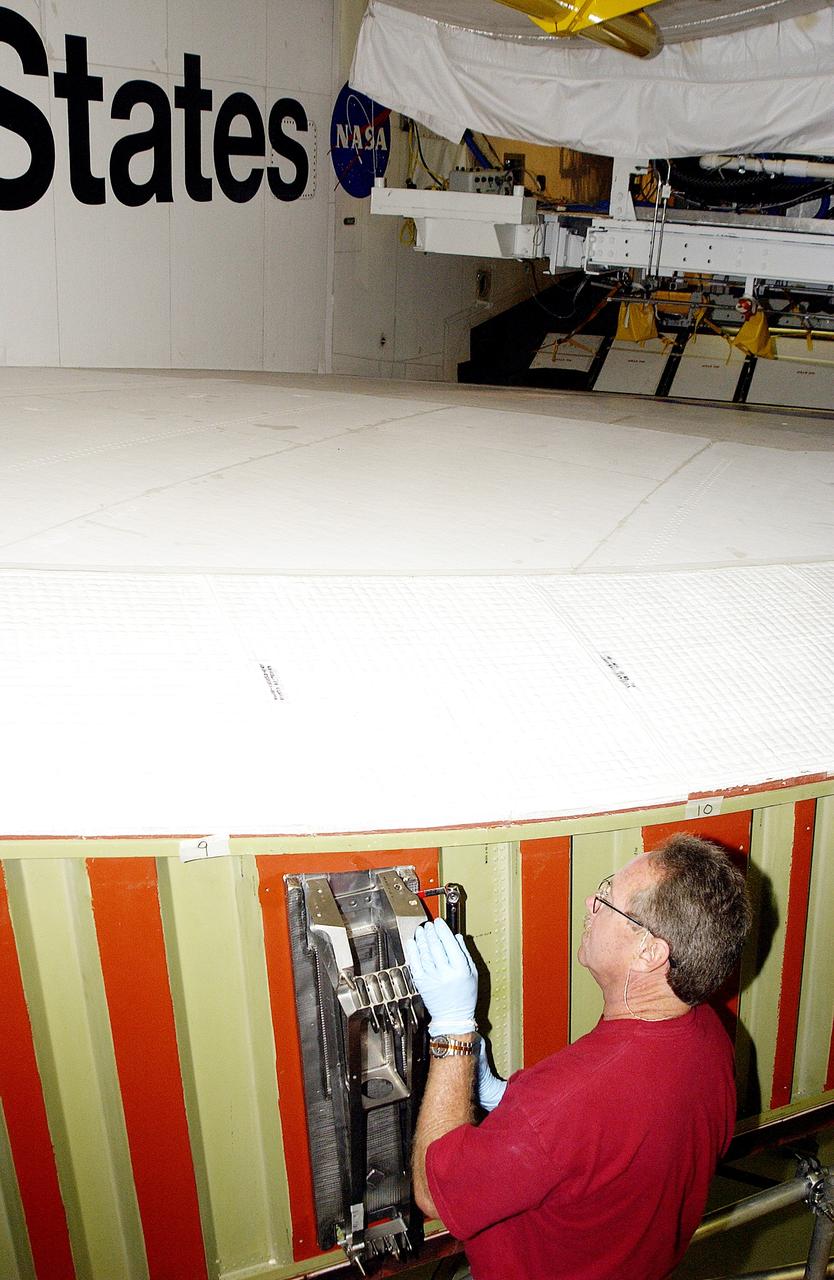 KENNEDY SPACE CENTER, FLA. -  In the Orbiter Processing Facility, Mike Hyatt, with United Space Alliance, installs a spar on the wing of the orbiter Atlantis.  Reinforced Carbon Carbon (RCC) panels are mechanically attached to the wing with a series of floating joints - spars - to reduce loading on the panels caused by wing deflections. The aluminum and the metallic attachments are protected from exceeding temperature limits by internal insulation.