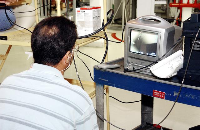 NASA image: KENNEDY SPACE CENTER, FLA. -  In the Orbiter Processing Facility,  Richard Parker, with NASA, watches a monitor showing images from a camera inserted beneath tiles of the orbiter Endeavour to inspect for corrosion.