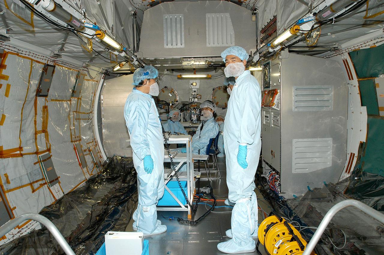 KENNEDY SPACE CENTER, FLA. -  In the Space Station Processing Facility, astronaut Soichi Noguchi (right), with the National Space Development Agency of Japan (NASDA), stands inside the Japanese Experiment Module (JEM) that is undergoing a Multi-Element Integrated Test (MEIT) with the U.S. Node 2.  The JEM, developed by NASDA, is Japan's primary contribution to the Station. It will enhance the unique research capabilities of the orbiting complex by providing an additional environment for astronauts to conduct science experiments. Noguchi is assigned to mission STS-114 as a mission specialist.  Node 2 provides attach locations for the Japanese laboratory, as well as European laboratory, the Centrifuge Accommodation Module and, eventually, Multipurpose Logistics Modules.  Installation of the module will complete the U.S. Core of the ISS.