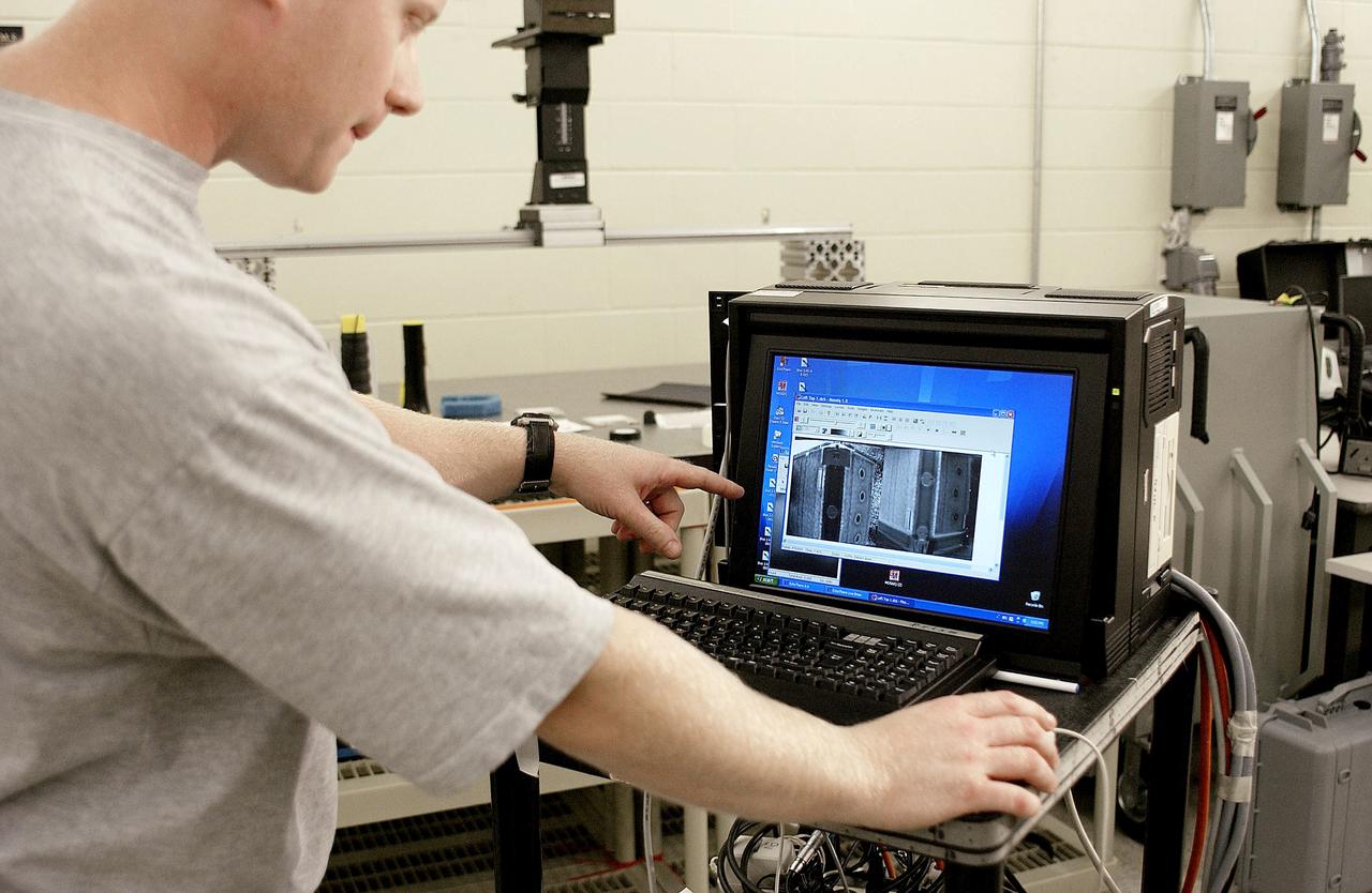 KENNEDY SPACE CENTER, FLA. - In the Vehicle Assembly Building, Jim Landy, NDE specialist, examines flight crew lockers using flash thermography. He is screening the lockers for hidden damage underneath dings and dents that might occur during handling.