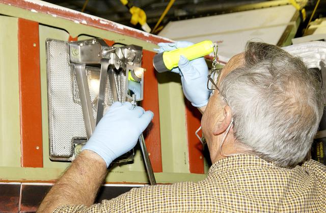 NASA image: KENNEDY SPACE CENTER, FLA. - In the Orbiter Processing Facility, Jerry Belt, with United Space Alliance, checks a spar attachment on the wing of the orbiter Atlantis before installing Reinforced Carbon Carbon (RCC) panels on the wing.  The spars - floating joints - reduce loading on the panels caused by wing deflections.  The gray carbon composite RCC panels have sufficient strength to withstand the aerodynamic forces experienced during launch and reentry, which can reach as high as 800 pounds per square foot.  The operating range of RCC is from minus 250º F to about 3,000º F, the temperature produced by friction with the atmosphere during reentry.