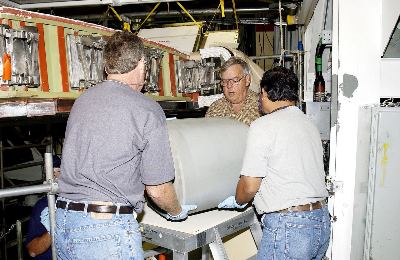 KENNEDY SPACE CENTER, FLA. - In the Orbiter Processing Facility, United Space Alliance workers Mike Hyatt (left) Jerry Belt (center), and Saul Ngy (right), lift a Reinforced Carbon Carbon (RCC) panel they will attach to the leading edge of the wing of the orbiter Atlantis.  The gray carbon composite RCC panels have sufficient strength to withstand the aerodynamic forces experienced during launch and reentry, which can reach as high as 800 pounds per square foot.  The operating range of RCC is from minus 250º F to about 3,000º F, the temperature produced by friction with the atmosphere during reentry.