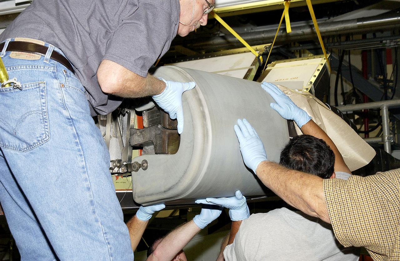 KENNEDY SPACE CENTER, FLA. - In the Orbiter Processing Facility, United Space Alliance workers Mike Hyatt (left) Saul Ngy (center) and Jerry Belt (right) lift a Reinforced Carbon Carbon (RCC) panel to attach onto the leading edge of the wing of the orbiter Atlantis.  The gray carbon composite RCC panels have sufficient strength to withstand the aerodynamic forces experienced during launch and reentry, which can reach as high as 800 pounds per square foot.  The operating range of RCC is from minus 250º F to about 3,000º F, the temperature produced by friction with the atmosphere during reentry.