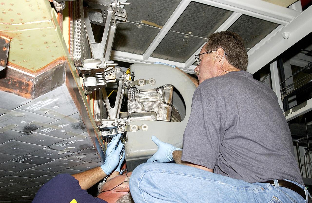 KENNEDY SPACE CENTER, FLA. -  In the Orbiter Processing Facility, United Space Alliance worker Mike Hyatt (right) attaches a Reinforced Carbon Carbon (RCC) panel onto the leading edge of the wing of the orbiter Atlantis.  The gray carbon composite RCC panels have sufficient strength to withstand the aerodynamic forces experienced during launch and reentry, which can reach as high as 800 pounds per square foot. The operating range of RCC is from minus 250º F to about 3,000º F, the temperature produced by friction with the atmosphere during reentry.