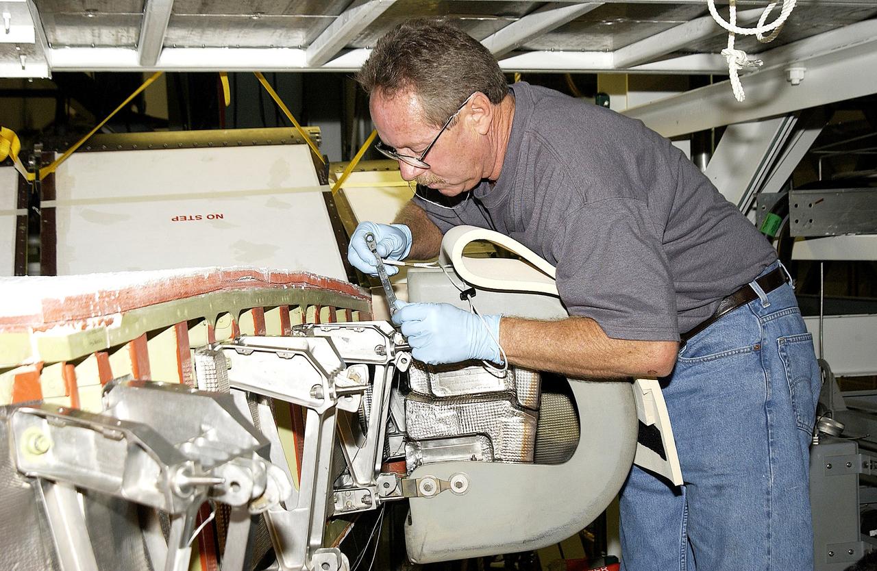 KENNEDY SPACE CENTER, FLA. -  In the Orbiter Processing Facility, United Space Alliance worker Mike Hyatt attaches a Reinforced Carbon Carbon (RCC) panel onto the leading edge of the wing of the orbiter Atlantis.  The gray carbon composite RCC panels have sufficient strength to withstand the aerodynamic forces experienced during launch and reentry, which can reach as high as 800 pounds per square foot. The operating range of RCC is from minus 250º F to about 3,000º F, the temperature produced by friction with the atmosphere during reentry.