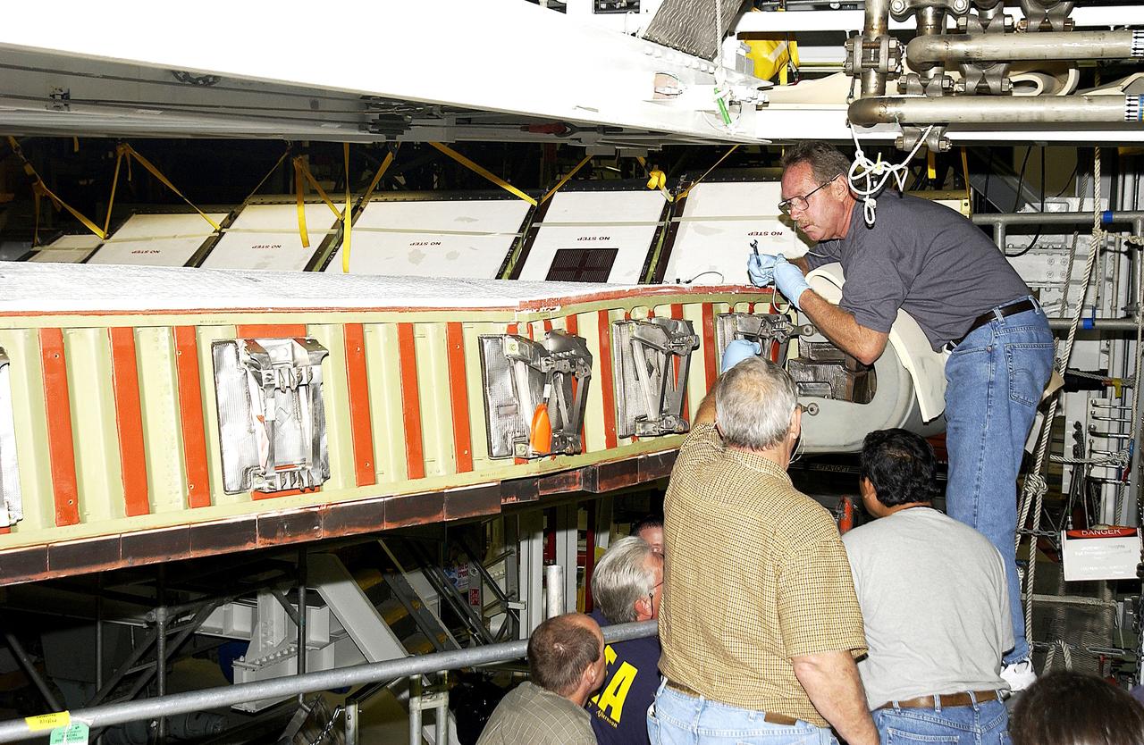 KENNEDY SPACE CENTER, FLA. -  In the Orbiter Processing Facility, United Space Alliance worker Mike Hyatt (above) attaches a Reinforced Carbon Carbon (RCC) panel onto the leading edge of the wing of the orbiter Atlantis.  The gray carbon composite RCC panels have sufficient strength to withstand the aerodynamic forces experienced during launch and reentry, which can reach as high as 800 pounds per square foot.  The operating range of RCC is from minus 250º F to about 3,000º F, the temperature produced by friction with the atmosphere during reentry.
