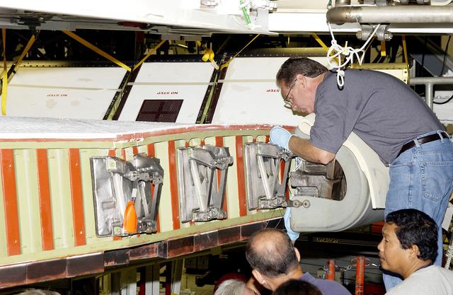 NASA image: KENNEDY SPACE CENTER, FLA. - In the Orbiter Processing Facility, United Space Alliance worker Mike Hyatt (above) completes installation of a Reinforced Carbon Carbon (RCC) panel onto the leading edge of the wing of the orbiter Atlantis.  The gray carbon composite RCC panels have sufficient strength to withstand the aerodynamic forces experienced during launch and reentry, which can reach as high as 800 pounds per square foot. The operating range of RCC is from minus 250º F to about 3,000º F, the temperature produced by friction with the atmosphere during reentry.