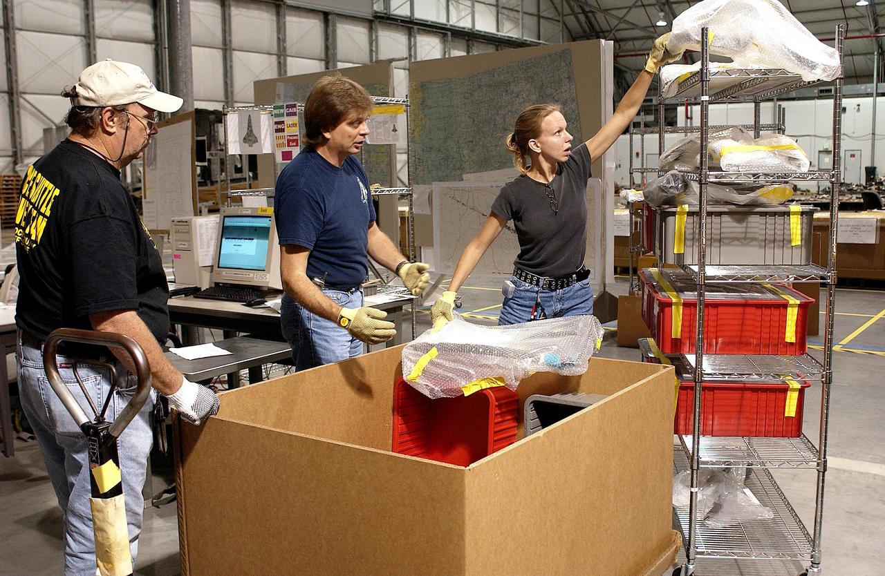 KENNEDY SPACE CENTER, FLA. - James Harrison (left), Jack Nowling (center) and Amy Norris (right) pack up part of the debris stored in the Columbia Debris Hangar.  An area of the Vehicle Assembly Building is being prepared to store the debris.  About 83,000 pieces were shipped to KSC during search and recovery efforts in East Texas.