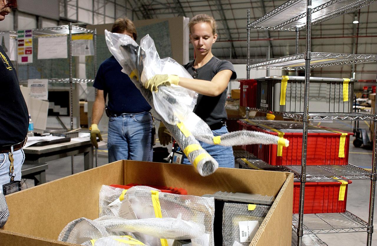 KENNEDY SPACE CENTER, FLA. - James Harrison (left), Jack Nowling (center) and Amy Norris (right) pack up some of the debris stored in the Columbia Debris Hangar.  About 83,000 pieces were shipped to KSC during search and recovery efforts in East Texas. An area of the Vehicle Assembly Building is being prepared to store the debris.