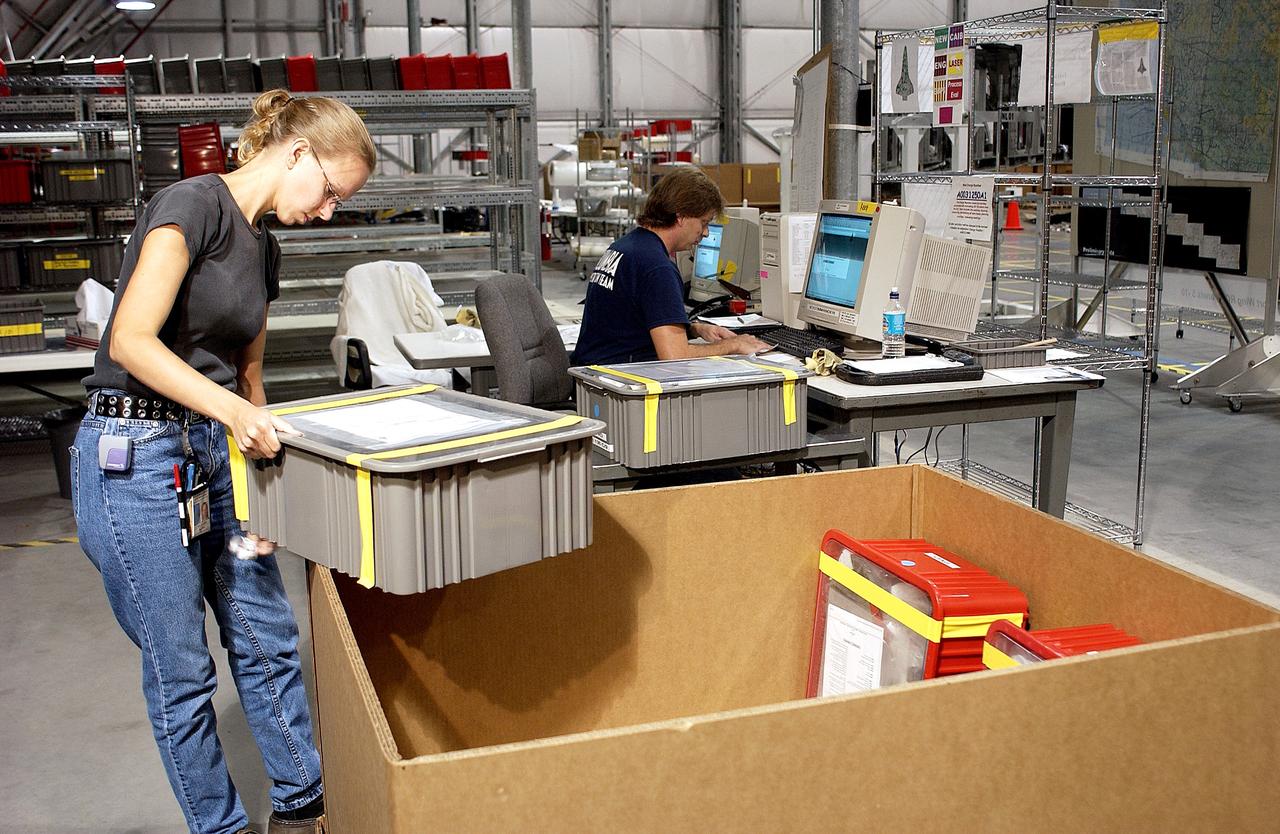 KENNEDY SPACE CENTER, FLA. -  Amy Norris (left) packs some of the debris stored in the Columbia Debris Hangar.  Jack Nowling works on the computer.  About 83,000 pieces of debris were shipped to KSC during search and recovery efforts in East Texas. That represents about 38 percent of the dry weight of Columbia, equaling almost 85,000 pounds.  An area of the Vehicle Assembly Building is being prepared to store the debris.
