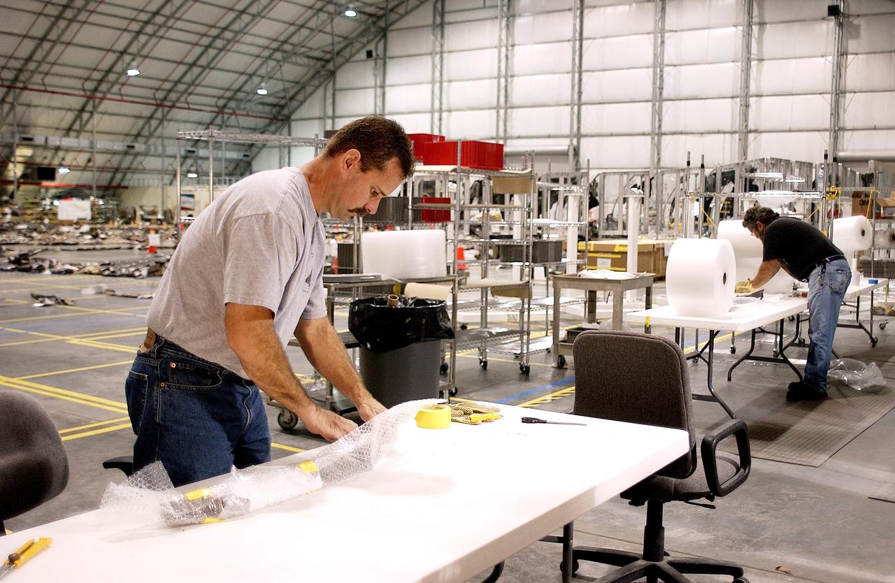 KENNEDY SPACE CENTER, FLA. -In the Columbia Debris Hangar, Don Eitel (left) wraps pieces of Columbia debris for storage.  About 83,000 pieces of debris were shipped to KSC during search and recovery efforts in East Texas. That represents about 38 percent of the dry weight of Columbia, equaling almost 85,000 pounds.  An area of the Vehicle Assembly Building is being prepared to store the debris.