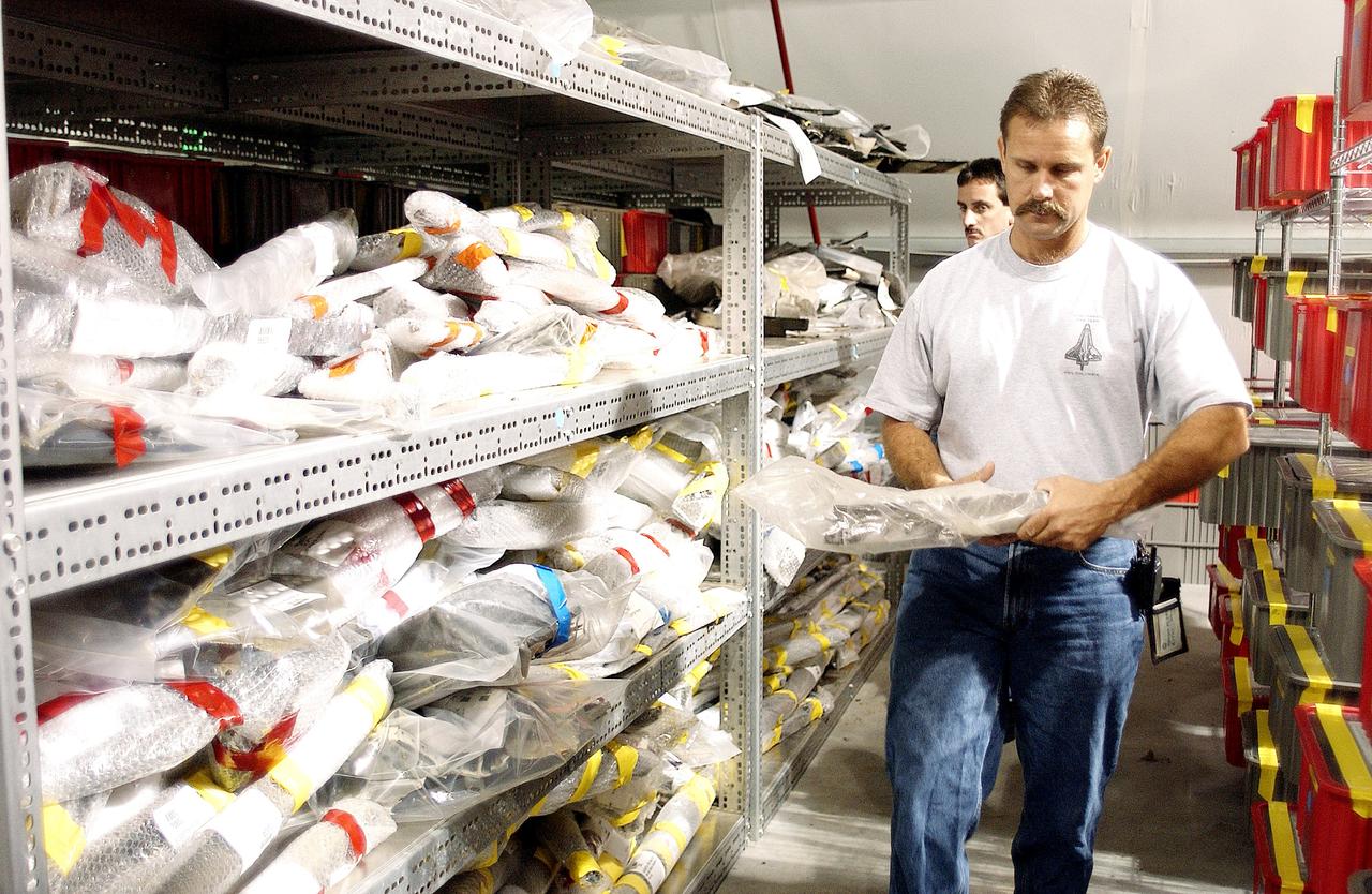 KENNEDY SPACE CENTER, FLA. -  In the Columbia Debris Hangar,  Don Eitel (in front) and Jim Delie carry pieces of debris to be packed into storage boxes.  About 83,000 pieces of debris were shipped to KSC during search and recovery efforts in East Texas. That represents about 38 percent of the dry weight of Columbia, equaling almost 85,000 pounds.  An area of the Vehicle Assembly Building is being prepared to store the debris.