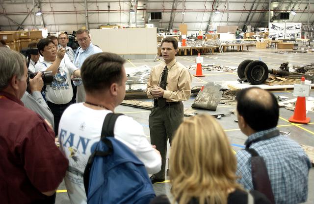 NASA image: KENNEDY SPACE CENTER, FLA. - In the Columbia Debris Hangar, Scott Thurston, NASA vehicle flow manager, addresses the media about efforts to pack the debris stored in the Columbia Debris Hangar.  More than 83,000  pieces of debris were shipped to KSC during search and recovery efforts in East Texas. That represents about 38 percent of the dry weight of Columbia, equaling almost 85,000 pounds. An area of the Vehicle Assembly Building is being prepared to store the debris permanently.