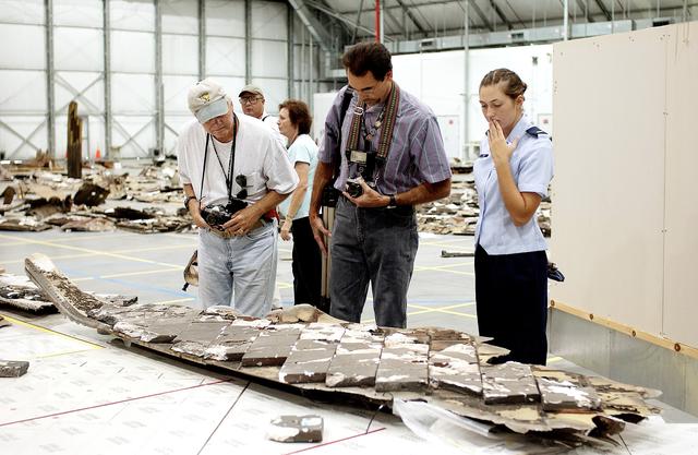 NASA image: KENNEDY SPACE CENTER, FLA. - During a media tour of the Columbia Debris Hangar, photographers look at pieces of tile collected during search and recovery efforts in East Texas.  About 83,000 pieces of debris from Columbia were shipped to KSC, which represents about 38 percent of the dry weight of Columbia, equaling almost 85,000 pounds.  The debris is being packaged for storage in an area of the Vehicle Assembly Building.