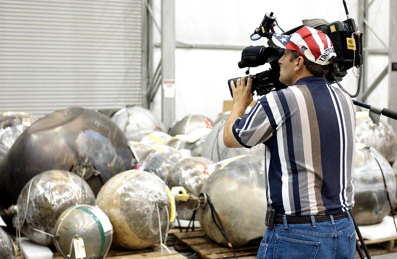 KENNEDY SPACE CENTER, FLA. - During a media tour of the Columbia Debris Hangar, a video cameraman records some of the debris collected from search and recovery efforts in East Texas. About 83,000 pieces of debris from Columbia were shipped to KSC, which represents about 38 percent of the dry weight of Columbia, equaling almost 85,000 pounds.  The debris is being packaged for storage in an area of the Vehicle Assembly Building.