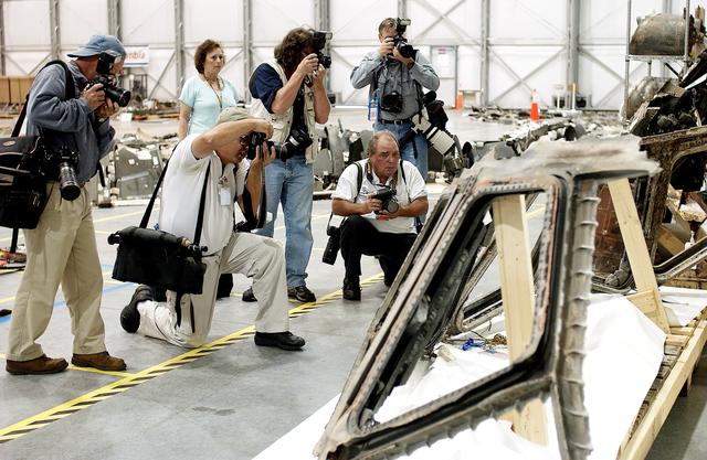 NASA image: KENNEDY SPACE CENTER, FLA. - During a media tour of the Columbia Debris Hangar, photographers focus on part of the cockpit collected from search and recovery efforts in East Texas. About 83,000 pieces of debris from Columbia were shipped to KSC, which represents about 38 percent of the dry weight of Columbia, equaling almost 85,000 pounds.  The debris is being packaged for storage in an area of the Vehicle Assembly Building.