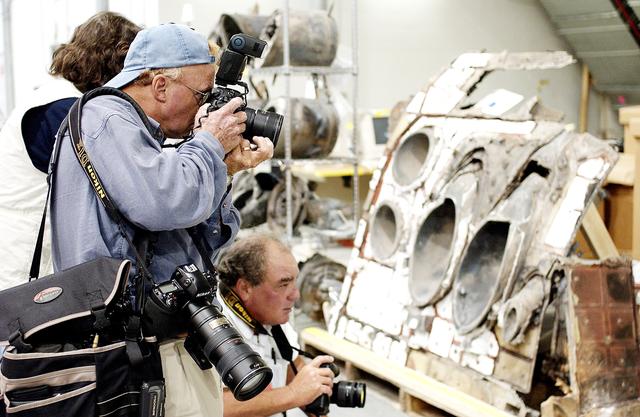 NASA image: KENNEDY SPACE CENTER, FLA. - During a media tour of the Columbia Debris Hangar, photographers focus on a piece of the debris collected from search and recovery efforts in East Texas. About 83,000 pieces of debris from Columbia were shipped to KSC, which represents about 38 percent of the dry weight of Columbia, equaling almost 85,000 pounds.  The debris is being packaged for storage in an area of the Vehicle Assembly Building.