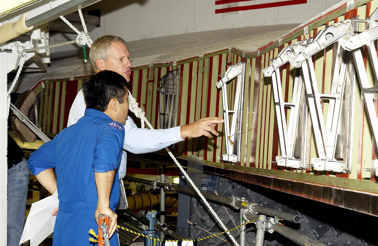 KENNEDY SPACE CENTER, FLA. - William Gaetjens (background), with the Vehicle Integration Test Team (VITT) directs Japanese astronaut Koichi Wakata’s attention to the spars installed on the wing of the orbiter Atlantis. Reinforced Carbon Carbon (RCC) panels are mechanically attached to the wing via the spars - a series of floating joints - to reduce loading on the panels caused by wing deflections. The aluminum and the metallic attachments are protected from exceeding temperature limits by internal insulation.