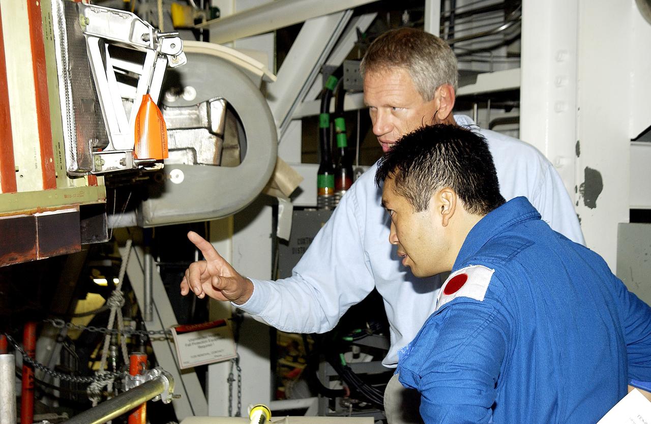 KENNEDY SPACE CENTER, FLA. - Japanese astronaut Koichi Wakata (front) listens to William Gaetjens, with the Vehicle Integration Test Team (VITT), who is providing details about the spar installation (left) on the wing of the orbiter Atlantis.  Reinforced Carbon Carbon (RCC) panels are mechanically attached to the wing via the spars - a series of floating joints - to reduce loading on the panels caused by wing deflections. The aluminum and the metallic attachments are protected from exceeding temperature limits by internal insulation.