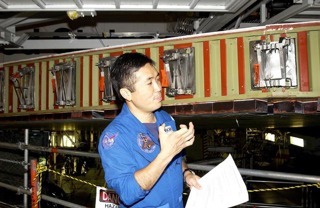 NASA image: KENNEDY SPACE CENTER, FLA. - Japanese astronaut Koichi Wakata gestures as he examines the spar installation (behind him) on the wing of the orbiter Atlantis.  Reinforced Carbon Carbon (RCC) panels are mechanically attached to the wing via the spars - a series of floating joints - to reduce loading on the panels caused by wing deflections. The aluminum and the metallic attachments are protected from exceeding temperature limits by internal insulation.