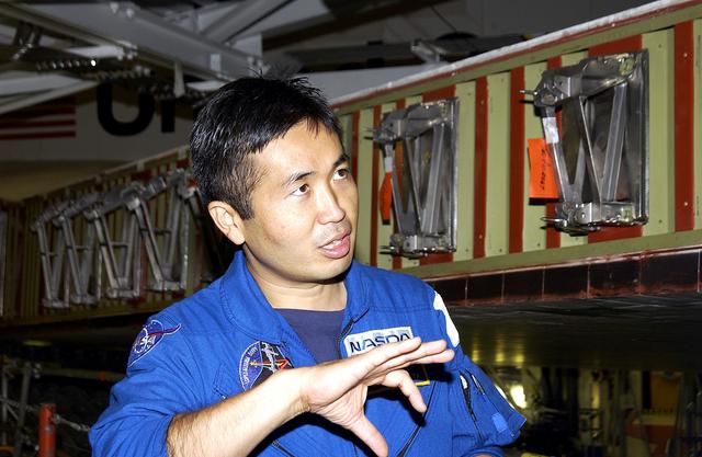 NASA image: KENNEDY SPACE CENTER, FLA. - Japanese astronaut Koichi Wakata gestures as he examines the spar installation (behind him) on the wing of the orbiter Atlantis.  Reinforced Carbon Carbon (RCC) panels are mechanically attached to the wing via the spars - a series of floating joints - to reduce loading on the panels caused by wing deflections. The aluminum and the metallic attachments are protected from exceeding temperature limits by internal insulation.